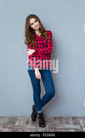 Jolie jeune femme bouclés en chemise à carreaux et jeans posing and smiling Banque D'Images