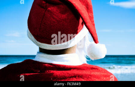 Santa Claus vu de derrière sur la plage face à l'horizon Banque D'Images