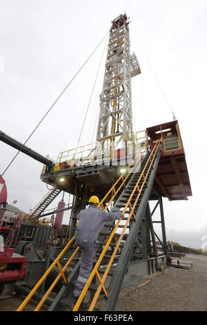 Un ingénieur en escalade sur une machine de forage dans un champ de gaz. Banque D'Images