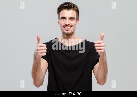 Heureux succès homme confiant en noir T-shirt showing Thumbs up Banque D'Images
