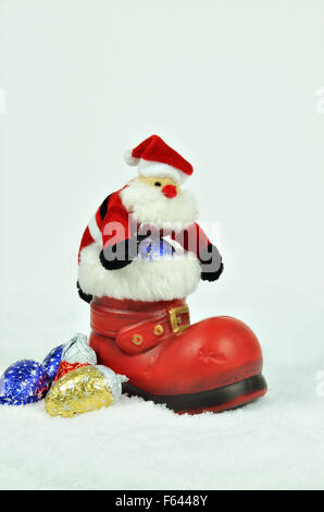 Père Noël avec branches de sapin à l'intérieur d'un soufflet rouge avec de la fourrure blanche découpage sur blanc, snowy background, Close up, vertical Banque D'Images