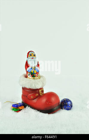 Père Noël avec branches de sapin à l'intérieur d'un soufflet rouge avec de la fourrure blanche découpage sur blanc, snowy background, Close up, vertical Banque D'Images