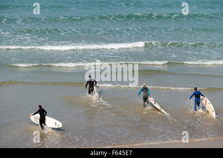Dans l'exécution de surfeurs à la mer à Newquay, Cornwall, Angleterre. Banque D'Images