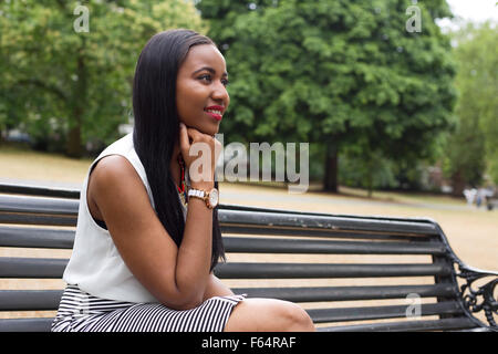 Jeune femme assise sur un banc dans le parc Banque D'Images