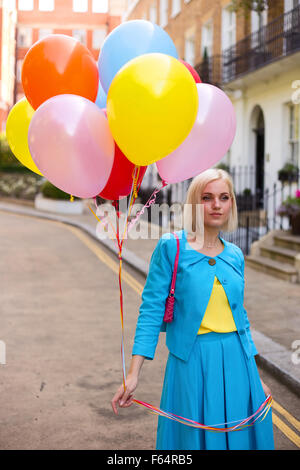 Jeune femme tenant un bouquet de ballons dans la rue Banque D'Images