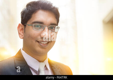 Close up portrait of handsome Asian Indian business man smiling, à l'extérieur moderne bureau bloc de construction, belle lumière dorée Banque D'Images