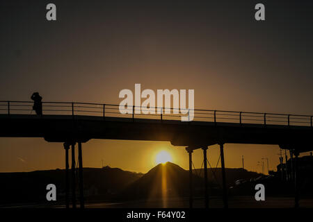 Un photographe s'aligne son tir alors que le soleil se lève sous la jetée victorienne à Saltburn-by-the-Sea en Angleterre, Royaume-Uni. Banque D'Images