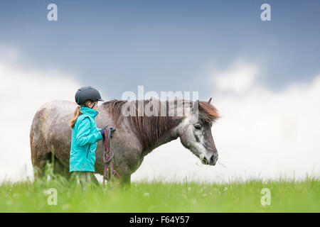 Cheval islandais. Fille avec dos-nu à côté de jeune jument grise sur un pâturage permanent. L'Autriche Banque D'Images