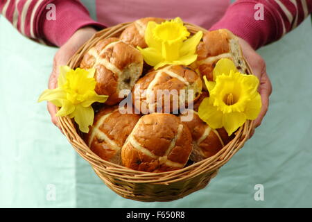 Une femme présente les brioches décorées avec des jonquilles dans un panier en osier rustique pour les fêtes de Pâques dans le nord de l'Angleterre, Royaume-Uni Banque D'Images