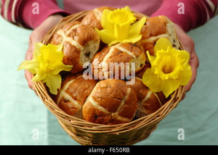 Une femme présente les brioches décorées avec des jonquilles dans un panier en osier rustique pour les fêtes de Pâques dans le nord de l'Angleterre, Royaume-Uni Banque D'Images