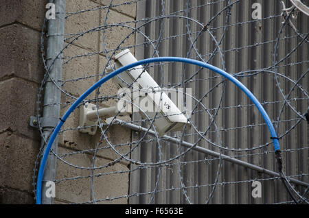 Caméra de vidéosurveillance ou de vidéosurveillance montée en hauteur sur un mur extérieur derrière un barbelé dans une installation de haute sécurité à Sydney, en Australie Banque D'Images