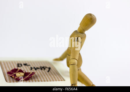 Marionnette en bois assis sur une boîte de bijoux sur un fond blanc Banque D'Images