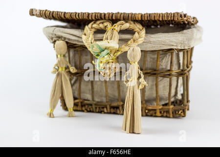 Deux figurines de paille en face d'une boîte en rotin vintage, sur un fond blanc Banque D'Images