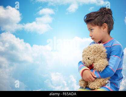 Sad little Girl with teddy bear toy plus de ciel bleu Banque D'Images