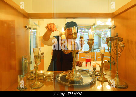 Femme juive religieuse s'allume les bougies du Chabbat dans sa maison. Banque D'Images