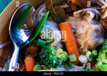 Close-up spoon, brocoli carottes et champignons dans un bol en céramique marron avec d'autres ingrédients de la soupe. Banque D'Images