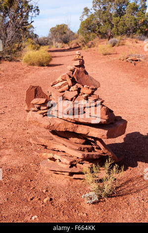 Petit cairn faites de roches rouges sur un sentier de randonnée. Banque D'Images