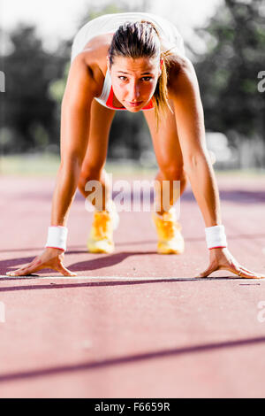 Belle femme sprinter se préparer pour l'exécuter au cours de l'été Banque D'Images