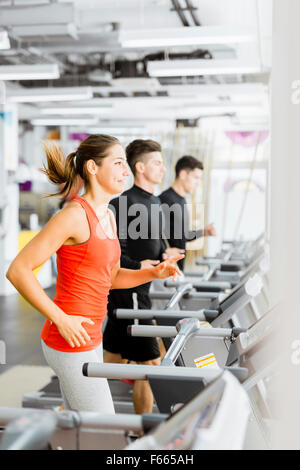 Groupe de jeunes gens qui couraient sur des tapis roulants dans un centre de remise en forme Banque D'Images