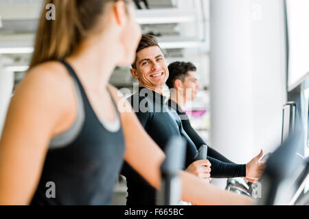 Bel homme et belle jeune femme à l'aide d'un en pas-à-pas d'une salle de sport et d'avoir une conversation Banque D'Images