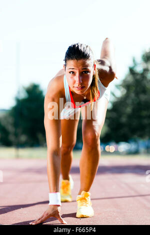 Belle femme sprinter se préparer pour l'exécuter au cours de l'été Banque D'Images