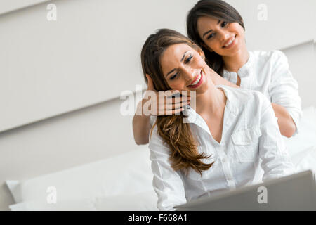 La mode superbe brunes dans shirts travaillant sur un ordinateur portable au lit Banque D'Images