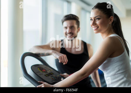 Belle et jeune les gens parler dans une salle de sport pendant l'entraînement et de brûler des calories Banque D'Images