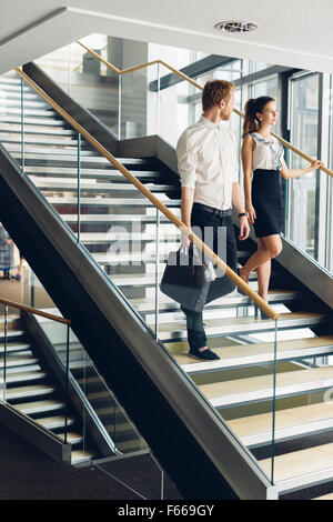 Businessman and businesswoman walking et prendre les escaliers dans un immeuble de bureaux modernes Banque D'Images