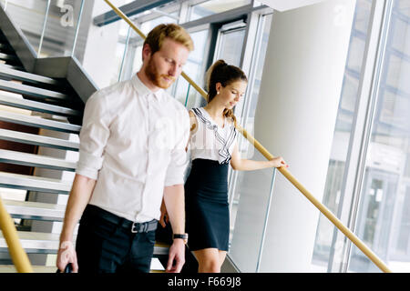 Businessman and businesswoman walking et prendre les escaliers dans un immeuble de bureaux modernes Banque D'Images