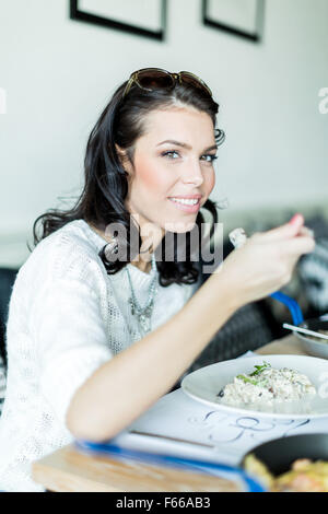 Belle jeune fille ayant un repas dans un restaurant et sur le point de prendre une bouchée Banque D'Images