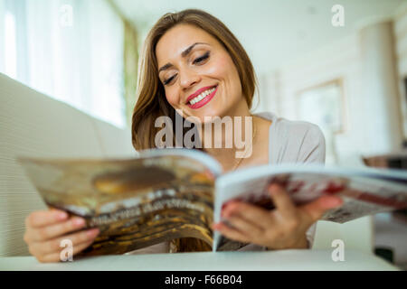 Belle femme sur un canapé-lit un document dans un élégant salon bien éclairé Banque D'Images