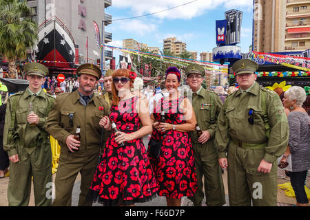 Benidorm, Espagne. 12 novembre 2015. Environ 40 000 fêtards de la foule, les rues de la nouvelle ville de Benidorm en costume pour le Britannique Fancy Dress Party dans la rue. qui est devenu un événement régulier le jour après la Fiesta espagnole majors. L'on voit ici, deux femmes en robes couvertes de pavot posent avec des hommes portant des vêtements militaires. Credit : Mick Flynn/Alamy Live News Banque D'Images