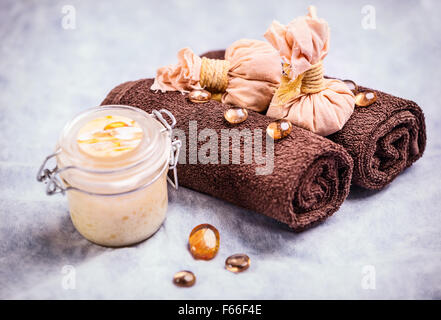 Spa treatment composition: container with body cream, towels, and decorative elements Banque D'Images