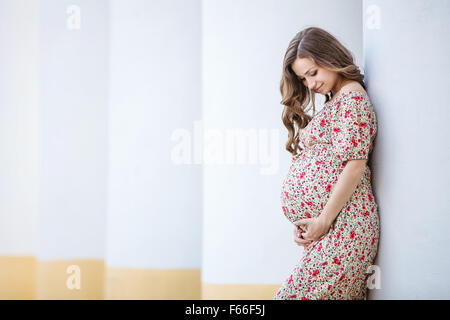 Happy pregnant woman leaning against la colonne de jour d'été Banque D'Images