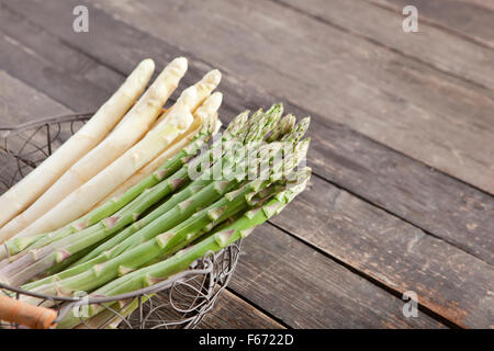 Les asperges vertes et blanches dans un panier sur fond de bois Banque D'Images