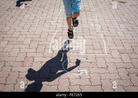 Les jambes de l'école primaire Garçon jouant à la marelle Banque D'Images