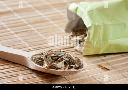 Les feuilles sèches de thé Citronnelle partie couché sur cuillère en bois sur le tapis, Cymbopogon citratus thé vert à base de pile à l'horizontale... Banque D'Images