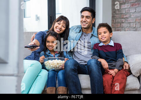 Young family eating popcorn tout en regardant la télévision Banque D'Images