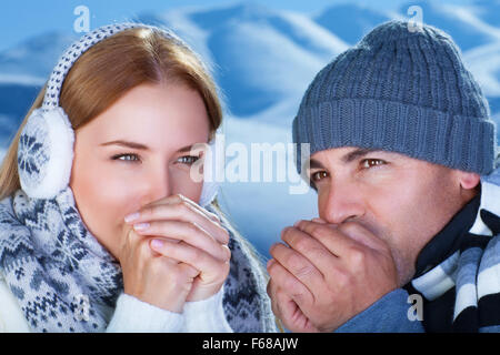 Closeup portrait of beautiful young couple essaie de se réchauffer les mains, passer les vacances d'hiver dans les montagnes enneigées Banque D'Images