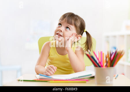 Fille enfant thoughful dessin avec crayons de couleur Banque D'Images