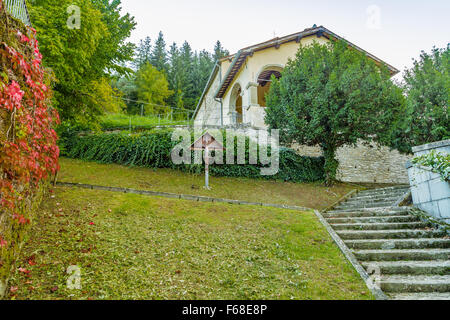 Croix de bois, près de Boston ivy dans le jardin en face de l'église dans un village de montagne médiéval en Toscane Banque D'Images