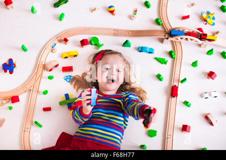 Enfant jouant avec un train, des rails et des voitures. Fer jouet pour les enfants. Jouets éducatifs pour les enfants de maternelle et d'âge préscolaire Banque D'Images