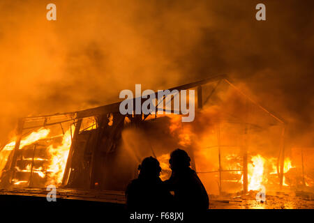 Les pompiers se tenir en face d'une salle de production d'une scierie dans Dipperz, Allemagne, 13 novembre 2015. Photo : Boris Roessler/dpa Banque D'Images