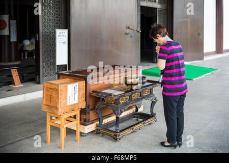 Femme en prière au temple Zojo Ji Shrine à Tokyo, Japon Banque D'Images