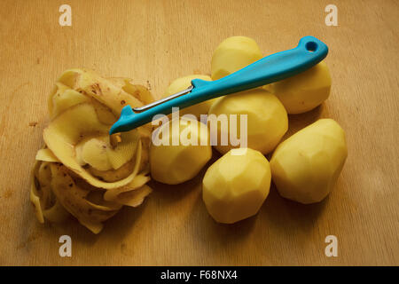 7 pommes de terre pelées, une poignée d'oranges et éplucheuse de pommes de terre de se coucher sur une vieille, a volé.vue horizontale Banque D'Images