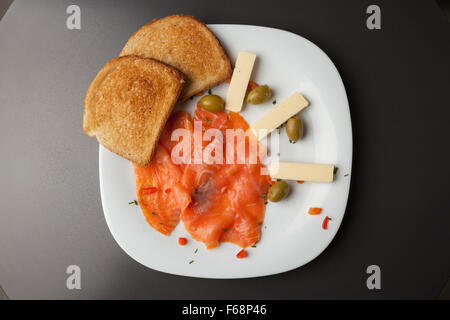 Filets de saumon fumé avec du pain grillé et des olives on white plate Banque D'Images