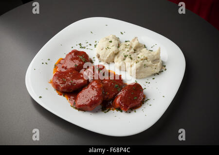 Porc en sauce rouge avec une purée de pommes de terre on white plate Banque D'Images