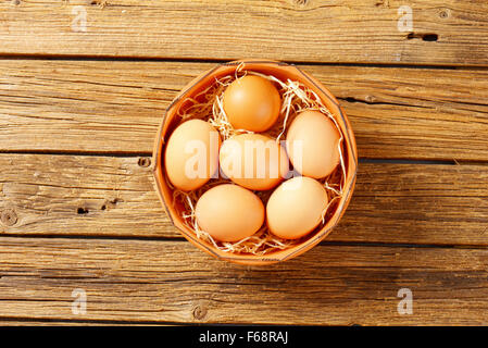 Fresh brown oeufs dans un bol en terre cuite sur la table en bois Banque D'Images