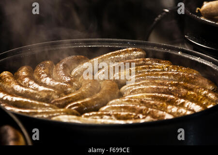 Lincoln, en Angleterre, Chriskindlemarkt, une casserole pleine de Lincolnshire sausage en préparation d'une nourriture un stand lors de la foire. Banque D'Images