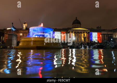 Londres, Royaume-Uni. 14 novembre 2015. Les fontaines et la Galerie nationale sont allumés dans le tricolore couleurs rouge, blanc et bleu comme des milliers de personnes se rassemblent à Trafalgar Square pour payer leur respect aux victimes en France et de montrer leur solidarité à la suite des attaques de Paris Banque D'Images